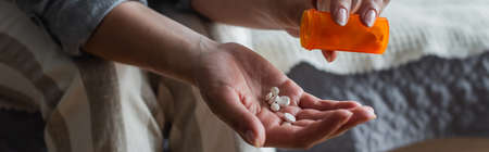 cropped view of woman with menopause holding bottle and pouring pills in hand, bannerの写真素材