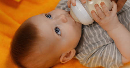 high angle view of infant boy drinking milk from baby bottleの写真素材