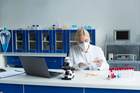 Researcher in white coat working with test tube and petri dish in laboratoryの写真素材