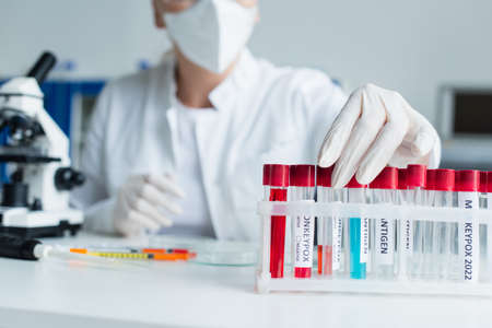 Cropped view of blurred scientist taking test tube with monkeypox lettering in lab