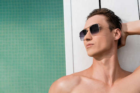 top view of man with bare shoulders resting in sunglasses at poolside