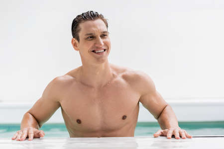 cheerful and sportive man looking away at poolsideの写真素材