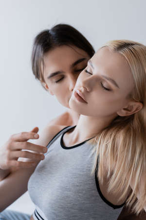 Blurred man kissing girlfriend in top isolated on greyの写真素材