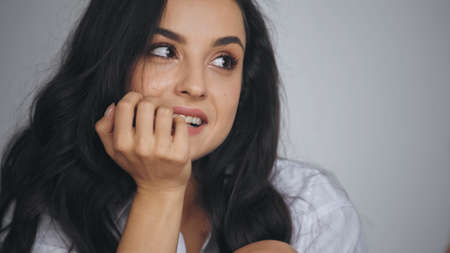 flirty young and brunette woman smiling while looking away at home