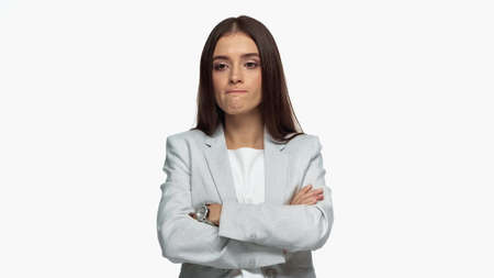 displeased businesswoman in grey blazer standing with crossed arms isolated on whiteの写真素材