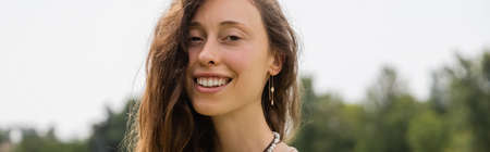 Cheerful brunette woman looking at camera outdoors, bannerの写真素材