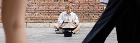 Man performing hang near hat on sidewalk on urban street in Venice, bannerの写真素材
