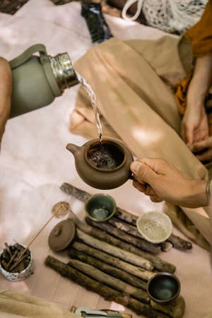 Cropped view of man pouring water in teapot near blurred tea bowls and wife in forestの写真素材