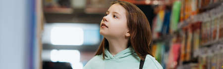child looking away in stationery store on blurred background, bannerの写真素材