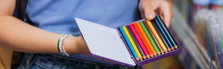 cropped view of woman in beaded bracelets holding box of color pencils, banner