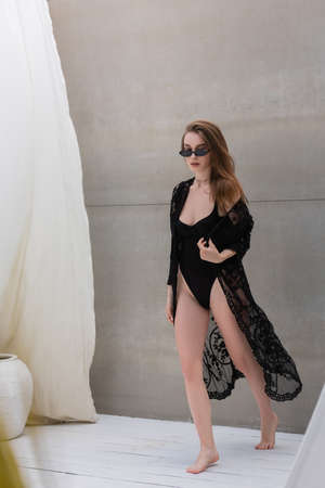 Stylish woman in swimwear and sunglasses walking at resortの写真素材