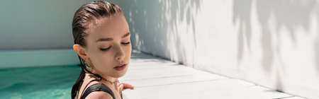 pretty young woman with wet hair swimming in pool with blue water, bannerの写真素材