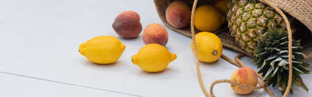Tropical fruits in straw handbag on floor at resort, banner