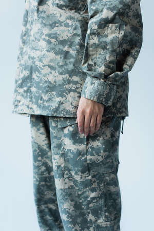Cropped view of servicewoman in camouflage uniform standing isolated on grey