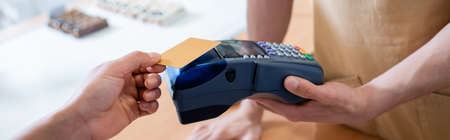 Cropped view of salesman holding terminal near african american customer with credit card in...