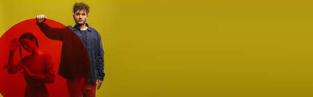 curly man in blue shirt holding round shape glass near woman isolated on green, bannerの写真素材