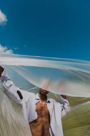 young african american man in shirt obscuring face with cellophane outdoors