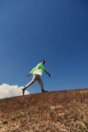 young african american man in fashionable clothes walking in field under blue sky