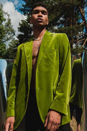 low angle view of african american man in green blazer near flexible mirror in parkの写真素材