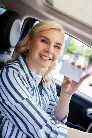Cheerful woman holding empty driver license in carの写真素材