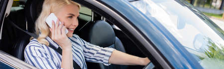 Happy woman talking on cellphone while driving auto, banner