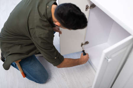 Overhead view of blurred man fixing hinge on door of kitchen cabinetの写真素材