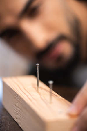 Blurred repairman looking at nails in wooden boardの写真素材