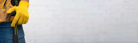 Cropped view of man in glove and tool belt holding hammer at home, bannerの写真素材