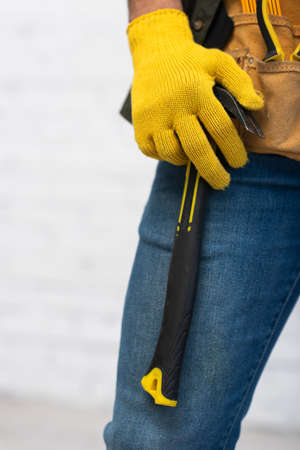 Cropped view of repairman in glove holding hammer on tool belt at homeの写真素材