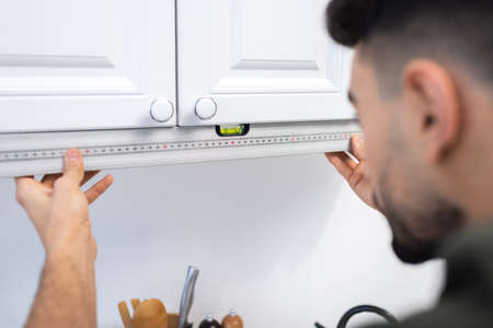 Blurred muslim craftsman measuring level of kitchen cabinet at homeの写真素材