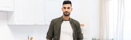 Young muslim man looking at camera at home, banner