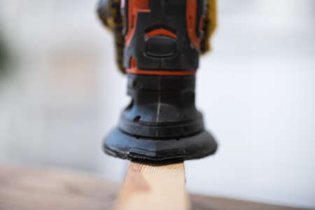 Close up view of blurred electric sander on wooden board at homeの写真素材