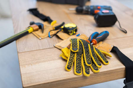 Gloves near blurred belt with tools on table at homeの写真素材