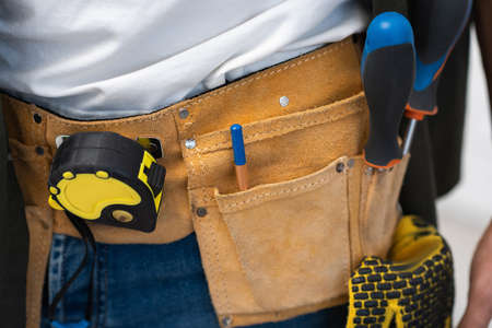 Cropped view of tools in belt on repairman at homeの写真素材