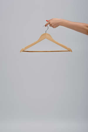 partial view of woman holding wooden hanger isolated on grayの写真素材