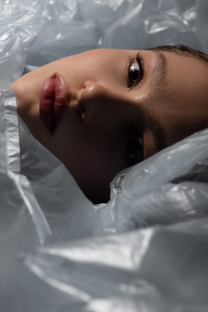 close up of model lying around plastic bags, recycle fashion concept