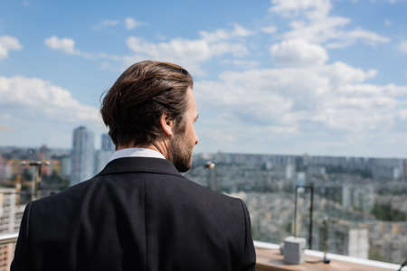 Side view of brunette groom looking away on terraceの写真素材