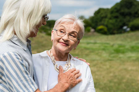 happy senior man in glasses putting hand on chest of smiling wifeの写真素材