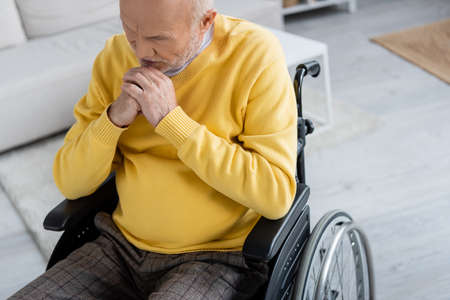 Sad elderly man sitting in wheelchair at home
