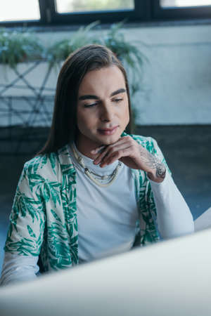 Young queer designer using blurred computer in officeの写真素材
