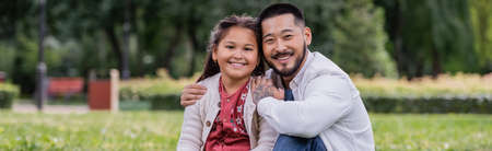 Asian parent hugging smiling preteen kid in park, bannerの写真素材