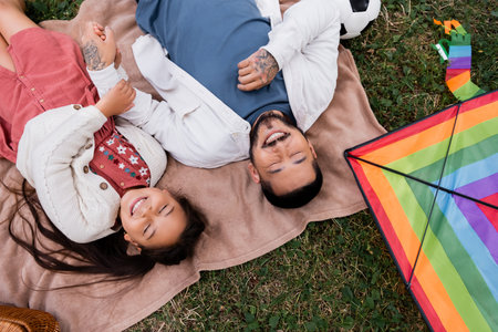 Top view of cheerful asian family holding hands near kite in parkの写真素材