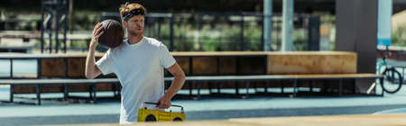 young basketball player with ball and record player walking near stadium, bannerの写真素材