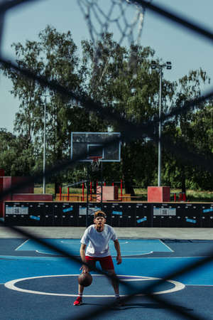 full length of basketball player training on modern court on blurred foregroundの写真素材