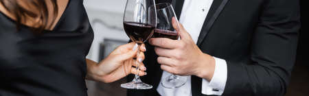 Cropped view of elegant couple toasting with wine at home, bannerの写真素材