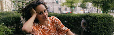 young woman in summer shirt sitting on bench in green park, banner