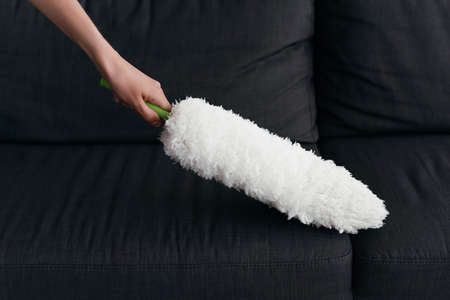 partial view of woman cleaning couch with dust brushの写真素材