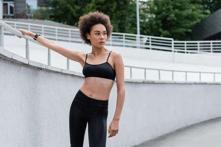 sportive african american woman with curly hair looking away on stadiumの写真素材