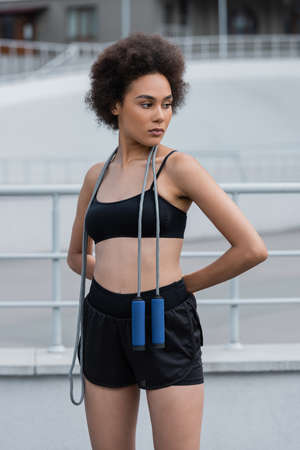 Fit african american sportswoman with jump rope looking away on stadium