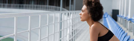 Side view of african american sportswoman in black top sitting on stadium, bannerの写真素材